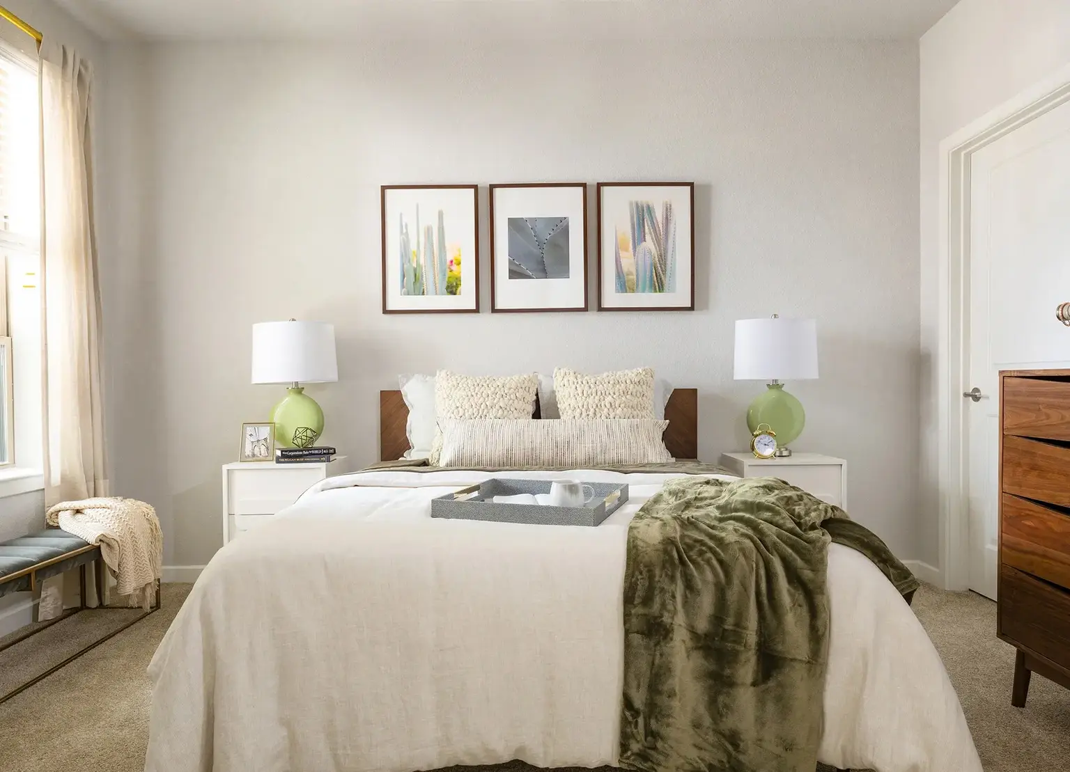 AVE Austin Furnished apartment bedroom with bed, end tables, and 3 generic abstract painting on wall 