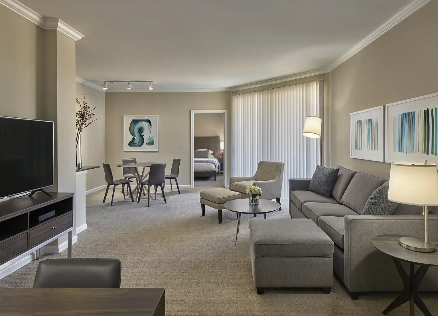 AVE Union furnished apartment with expansive living room, TV, large gray couch, eating nook in the background, and entrance to balcony
