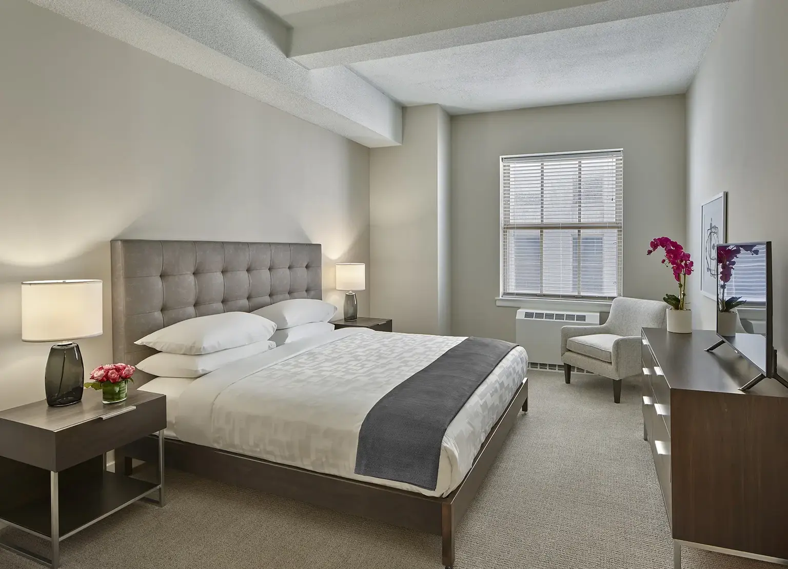 The Franklin Residences Philadelphia apartment bedroom with king bed, tv, and window with white blinds