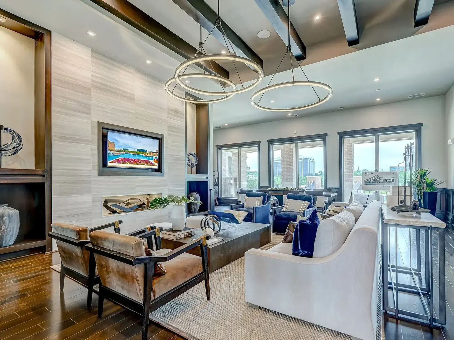 Spacious lounge area with chairs and couches and city view at AVE Las Colinas apartment building.