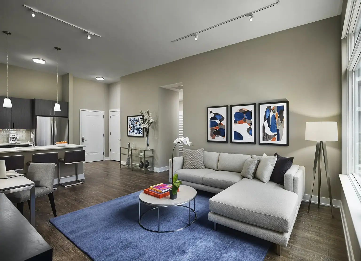 AVE Florham Park furnished apartment living room with gray couch and blue accents. Kitchen in the background