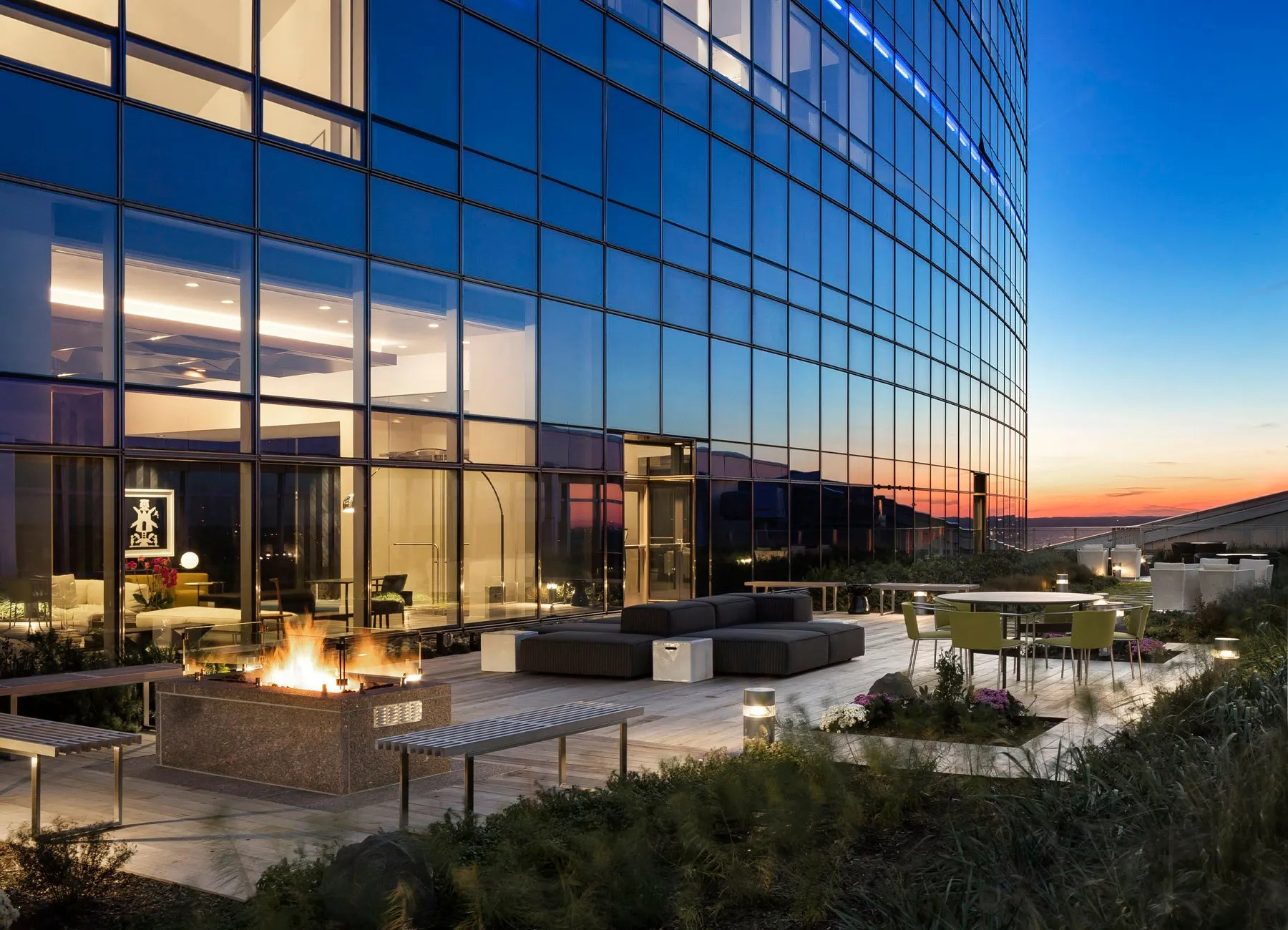 AKA University City terrace at dusk with glass building behind, foliage, seating, and views of Philadelphia 